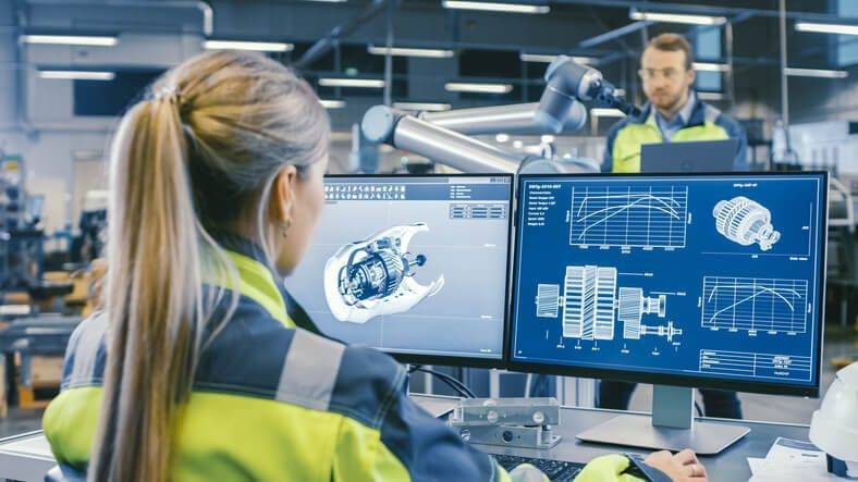 Two employees reviewing data on computer screens