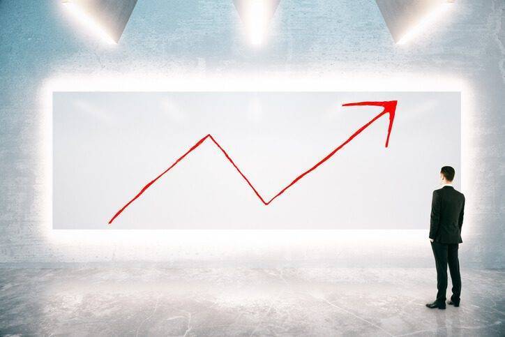 Man looking at digital wall with arrow trending up